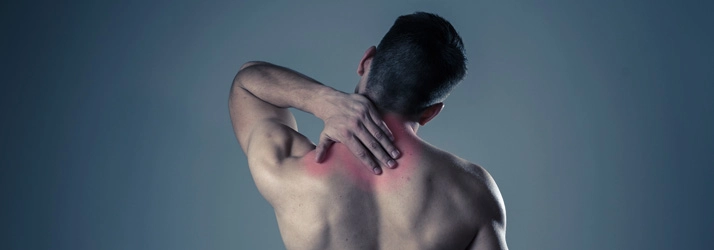 A person holding the back of the neck with visible redness, indicating neck pain or muscle strain.