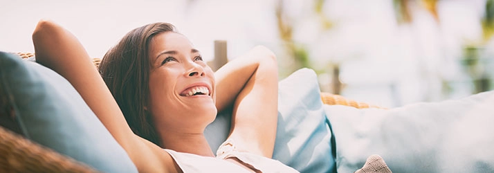 An individual reclining on a cushioned outdoor chair, representing relaxation and wellness.